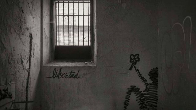 Inmates and a chaplain gathered in a prison room during a pastoral activity in Spain