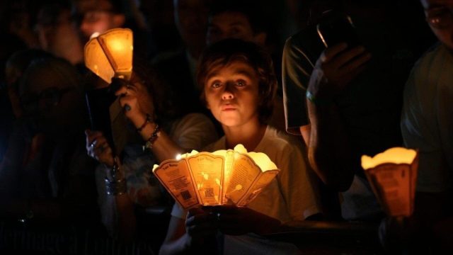 Pilgrims holding lit candles during the torchlight procession at the shrine of Lourdes, with Pope Leo XIV presiding