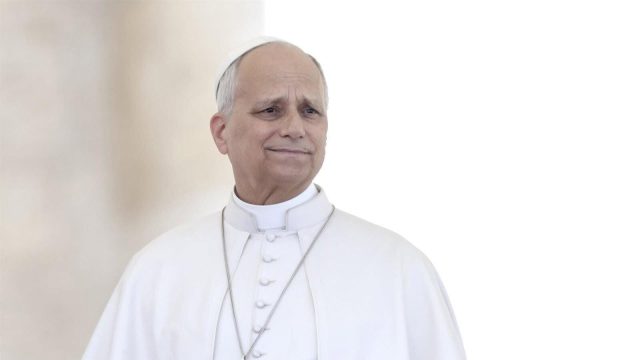 Pope Leo XIV smiling in white papal vestments as he greets people
