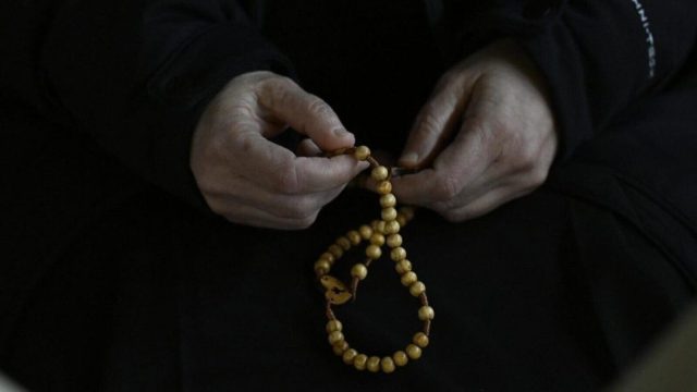 A Catholic priest in black clerical dress standing inside a church in Soria