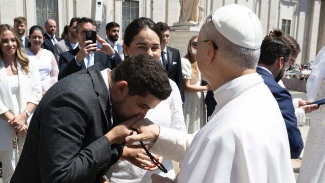 A young couple seated with a priest during a marriage preparation meeting at the Vatican