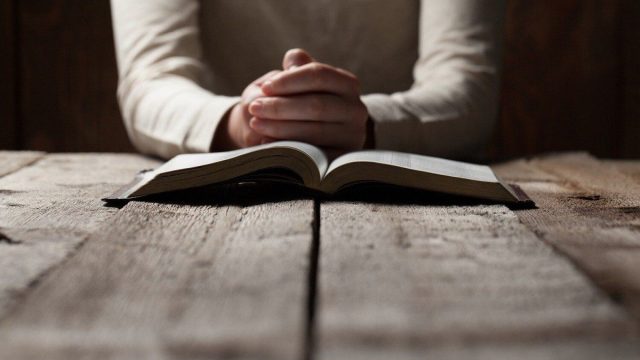 An open Bible beside a rainbow-colored LGBT flag