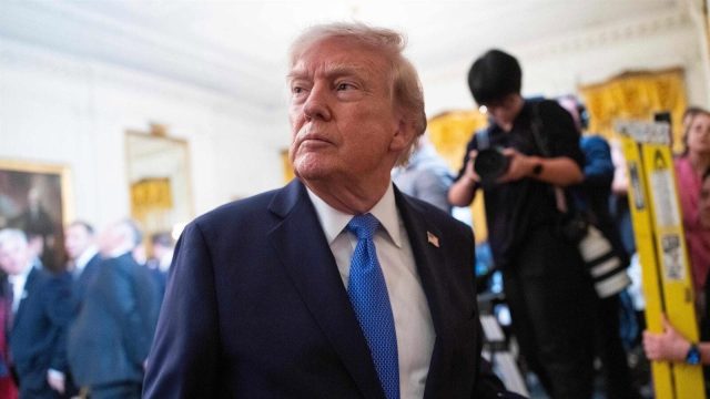 President Donald Trump stands with his head bowed in prayer alongside a group of Catholic bishops at the White House