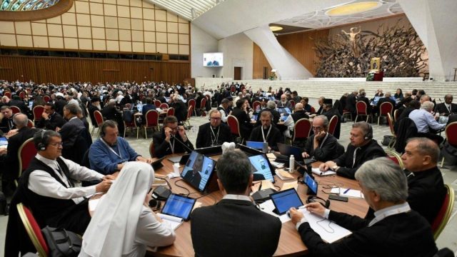 Delegates seated at tables during a synodal assembly session