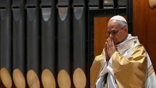 Pope Leo XIV in a white cassock, his hands raised as he speaks