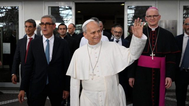 Pope Leo XIV smiling as he greets people after leaving the Gemelli hospital in Rome