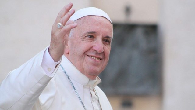 Pope Francis seated among participants at a synod assembly in the Vatican